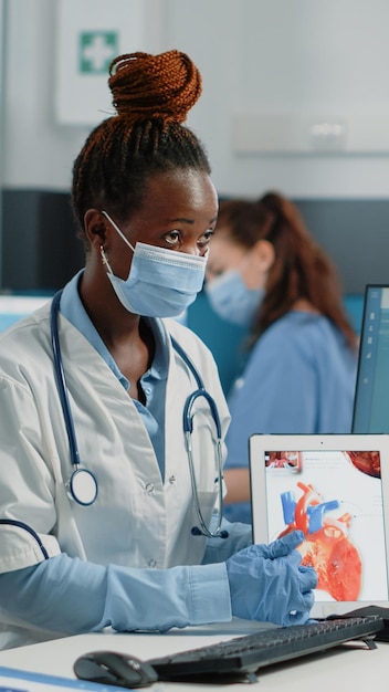 Photo docteur portant un masque montrant une tablette médicale