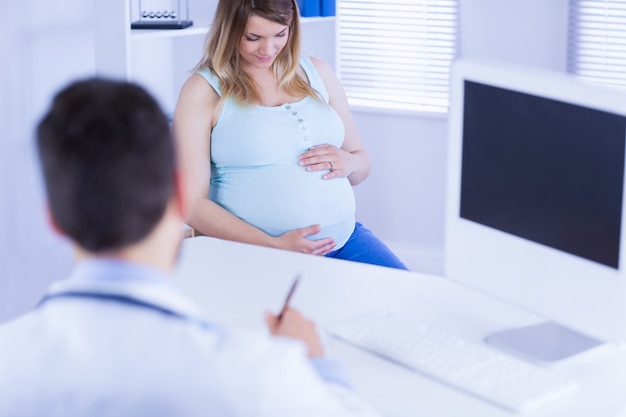 Docteur prendre des notes tout en écoutant une patiente enceinte