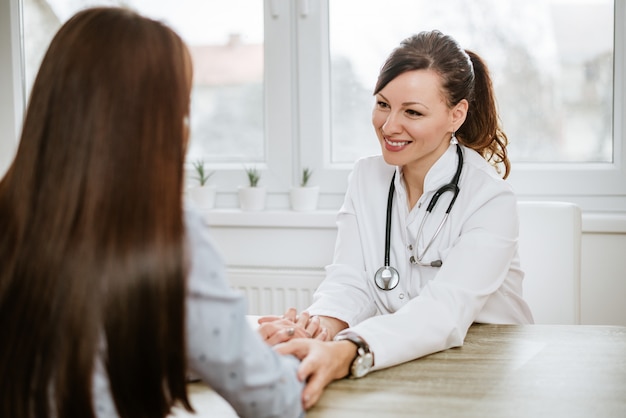 Docteur rassurant sa patiente assise au bureau.