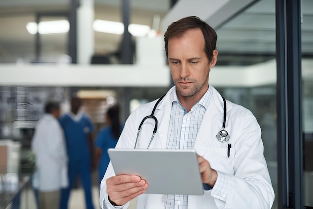 Docteur avec des recherches médicales sur une tablette numérique dans un hôpital et vérifier les effets secondaires des médicaments