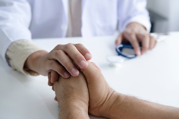 Docteur réconfortant le patient à la salle de consultation.