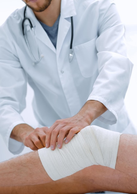 Docteur regardant le bandage sur la jambe du patient