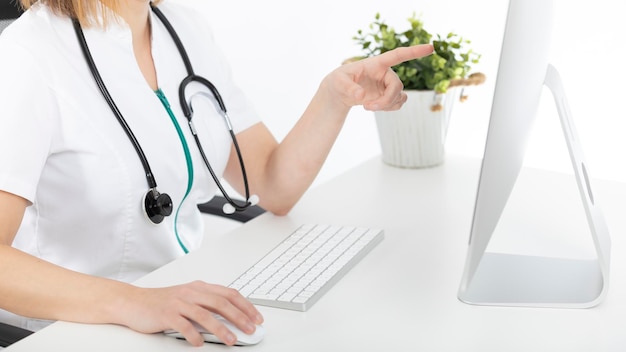 Photo docteur à son bureau regardant fixement l'ordinateur et pointant son doigt