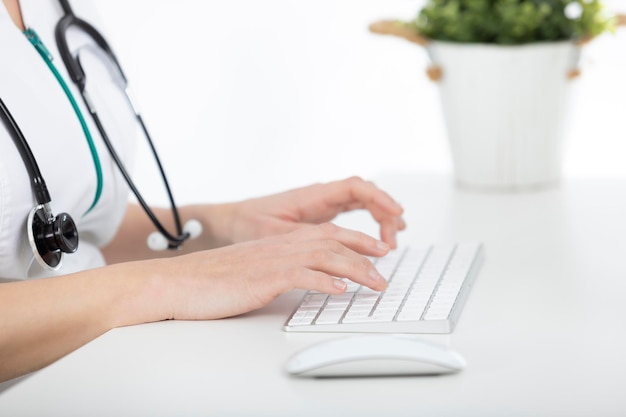 Photo docteur à son bureau tapant sur l'ordinateur