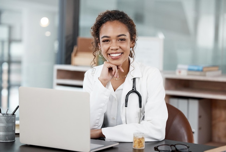 Photo docteur souriant ou portrait avec un ordinateur portable sur le bureau pour un calendrier de rendez-vous virtuel ou une réunion en ligne femme heureuse et technologie sur le lieu de travail pour la communication avec le client ou des conseils de santé sur les médias sociaux