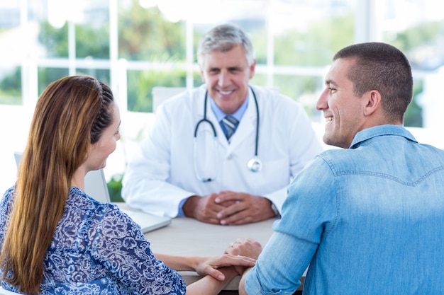 Docteur Souriante Regardant Un Couple Heureux En Cabinet Médical