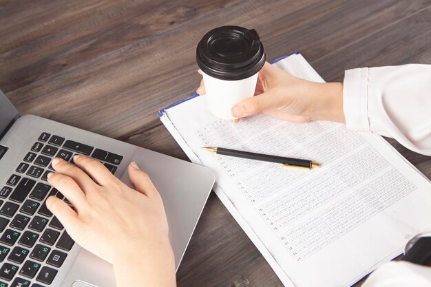 Docteur tenant un café devant un ordinateur portable