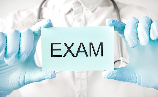 Docteur tenant la carte dans les mains et pointant le mot EXAMEN