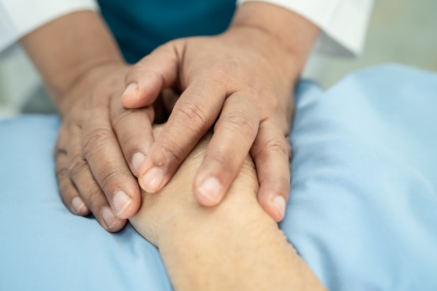 Docteur tenant des mains touchantes Patiente asiatique âgée ou âgée de vieille dame avec amour, soins, aide, encouragement et empathie à l'hôpital de soins infirmiers, concept médical fort et sain