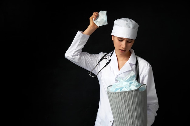 Docteur tenant un seau plein de masques faciaux utilisés, les jetant comme symbole de la fin de l'épidémie