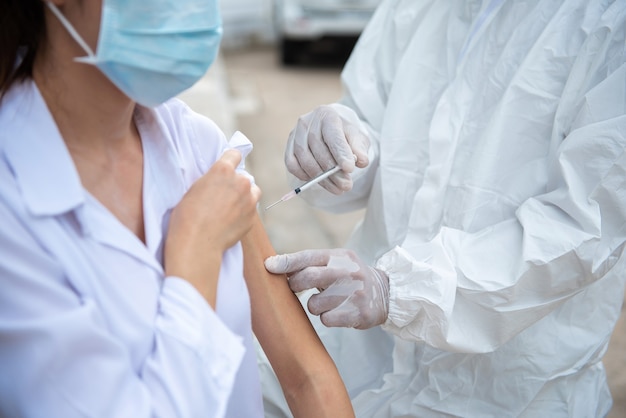 Docteur tenant une seringue avant de faire l'injection au patient dans un masque médical. Vaccin contre le Covid-19 ou le coronavirus