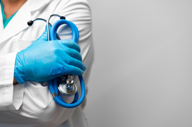 Docteur tenant un stéthoscope avec les bras croisés portant des gants bleus se bouchent