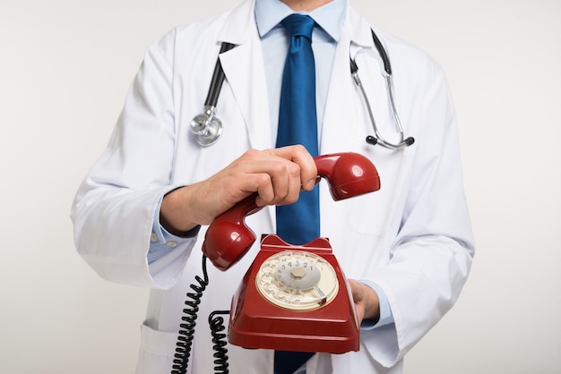 Docteur tenant un téléphone vintage rouge