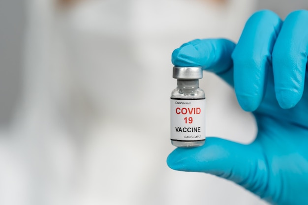 Docteur en tenue de protection EPI tenant une bouteille de vaccin contre le coronavirus (Covid-19)