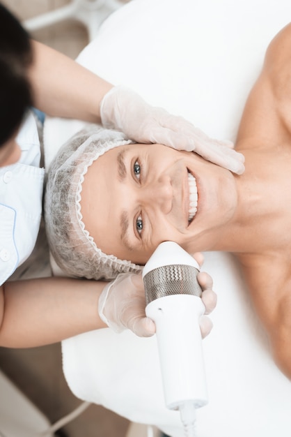 Photo docteur traite la peau d'un homme avec un photoépilateur moderne.