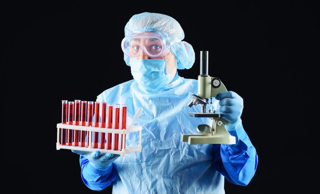 Docteur avec des tubes à essai sanguin et un microscope. Technicien de laboratoire analysant un échantillon de sang en clinique.