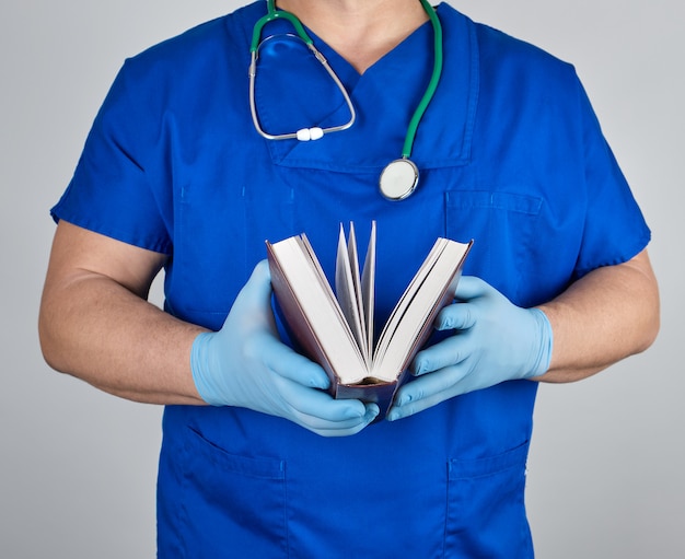 Docteur en uniforme bleu tient un livre ouvert dans ses mains