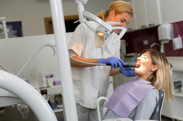 Docteur en uniforme vérifiant les dents de la patiente dans une clinique dentaire