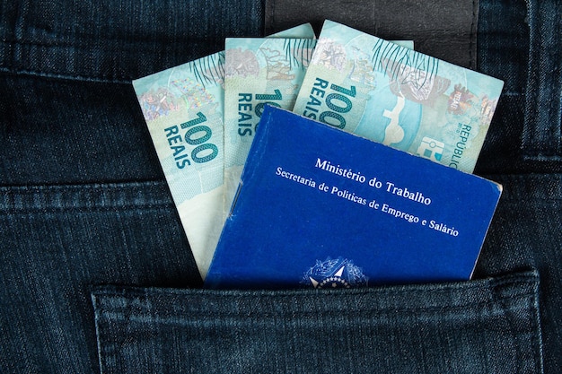 Document brésilien de travail et de sécurité sociale Carteira de Trabalho e Previdencia Social dans la poche de son jean avec cent billets de reais argent brésilien