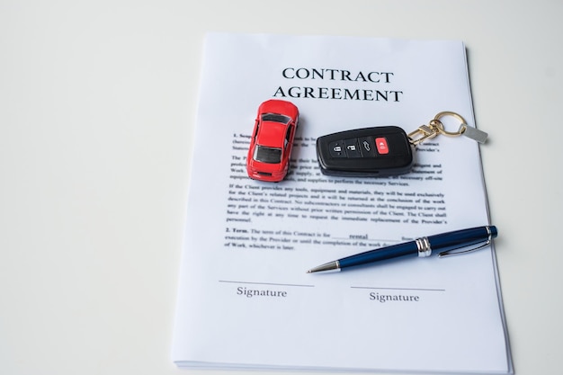 Document contractuel avec voiture et clé à distance achat et vente d'assurance location et concepts d'accord de contrat