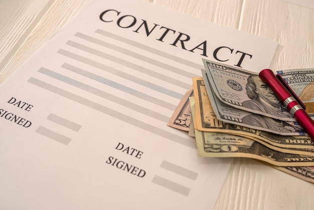 Document de contrat d'entreprise avec stylo et dollars debout sur le bureau