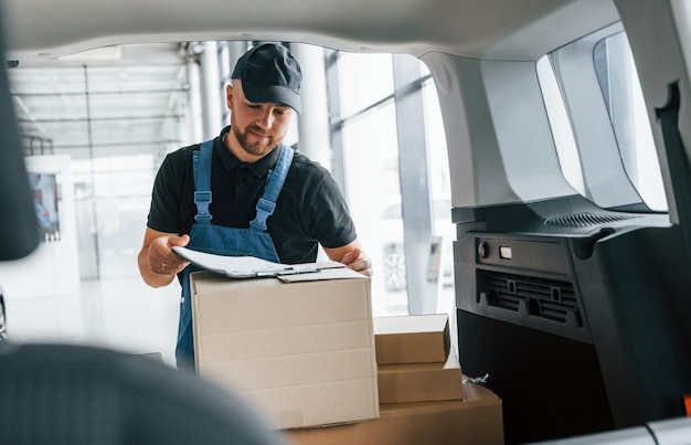 Avec document Le livreur en uniforme est à l'intérieur avec voiture et avec commande