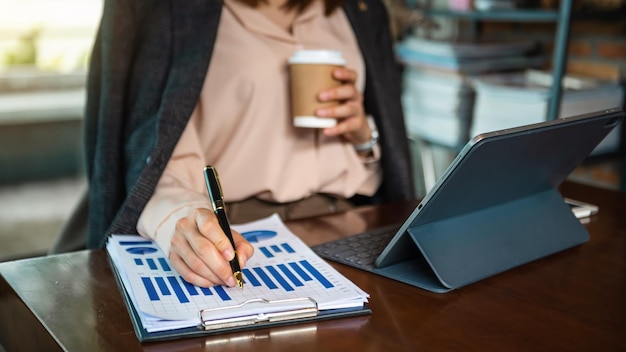 Documents d'affaires sur le bureau avec ordinateur portable et téléphone intelligent et diagramme d'affaires graphique et femme travaillant le matin lightxA