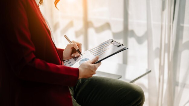 Documents commerciaux sur table de bureau avec téléphone intelligent et tablette numérique et graphique financier et femme travaillant au bureau