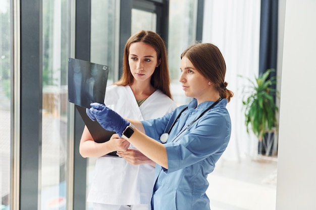 Avec des documents Deux médecins en uniforme debout à l'intérieur et travaillant ensemble