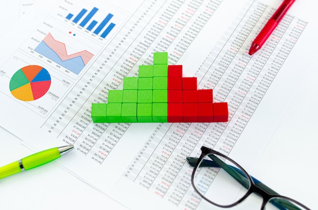 Documents financiers, avec des cubes verts disposés dans un graphique à colonnes comme concept de revenus, dépenses ou flux de trésorerie