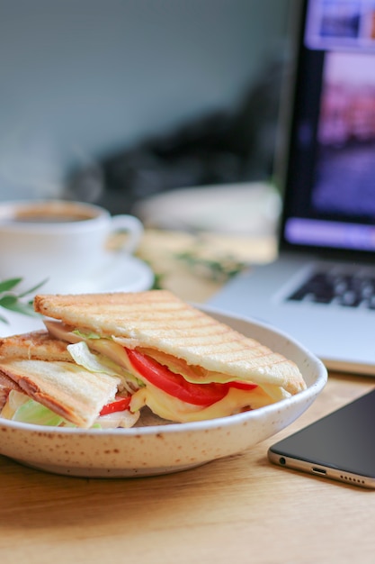 DOF peu profond de Sandwich végétarien avec ordinateur portable et café sur le dos flou