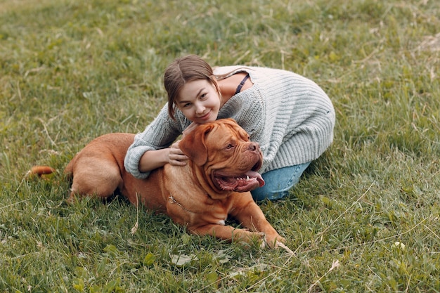 Dogue de Bordeaux ou Mastiff français avec la jeune femme au pré du parc extérieur.