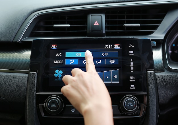 Doigt appuyant sur le bouton sur le climatiseur dans le tableau de bord de voiture moderne