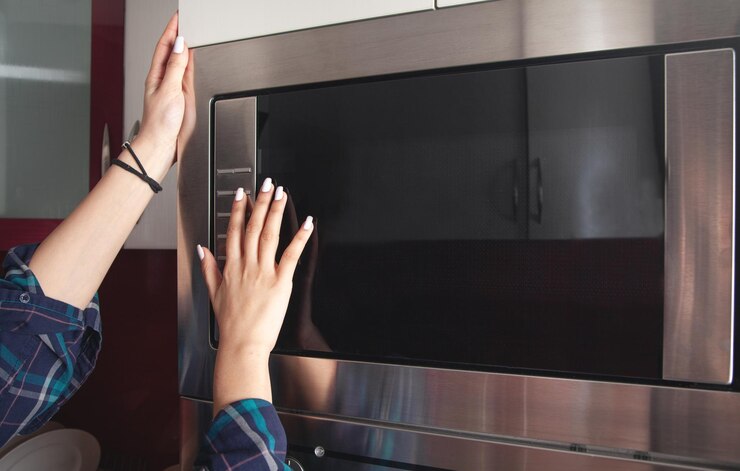 Doigt féminin touchant le bouton du four électrique dans la cuisine