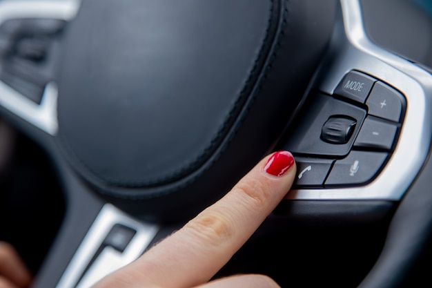 Doigt de la main féminine pousser le bouton d'appel téléphonique sur l'équipement du volant de la voiture moderne libre