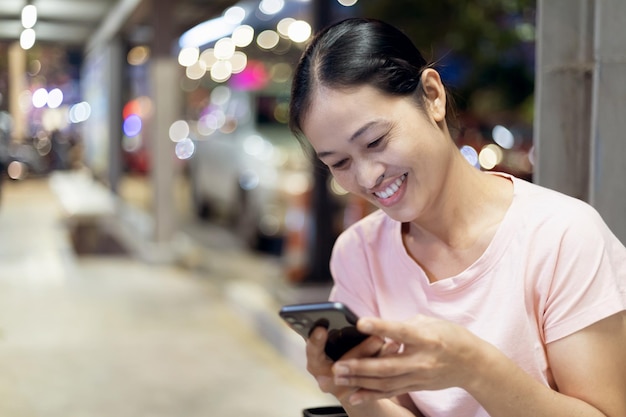 Doigt pointé sur l'écran du téléphone mobile messagerie texte gros plan personne touchant smartphone nuit ville lumière fille à l'aide de téléphone portable à la main gros plan internet en ligne