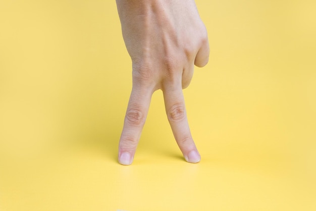 Doigts de femmes marchant sur fond jaune.