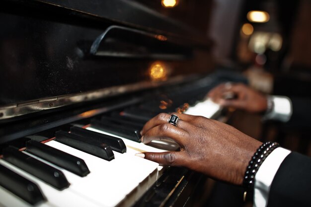 Les doigts d'un homme afro-américain en costume noir jouent du piano