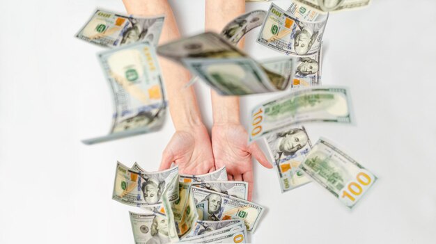 Photo des dollars volants tombent sur les mains d'une femme. focus flou. concept de richesse, de succès, de parrainage.