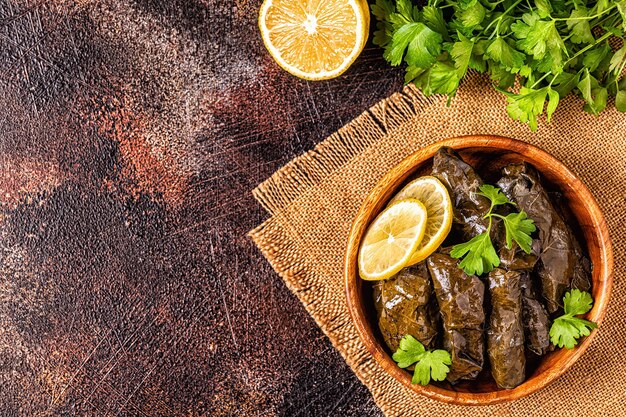 Dolma, feuilles de vigne farcies avec du riz et de la viande sur fond sombre, vue de dessus.