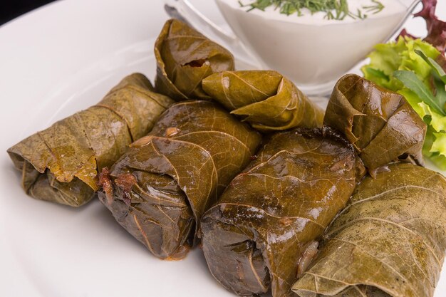 Dolma avec de la viande et de la crème sure sur une assiette blanche