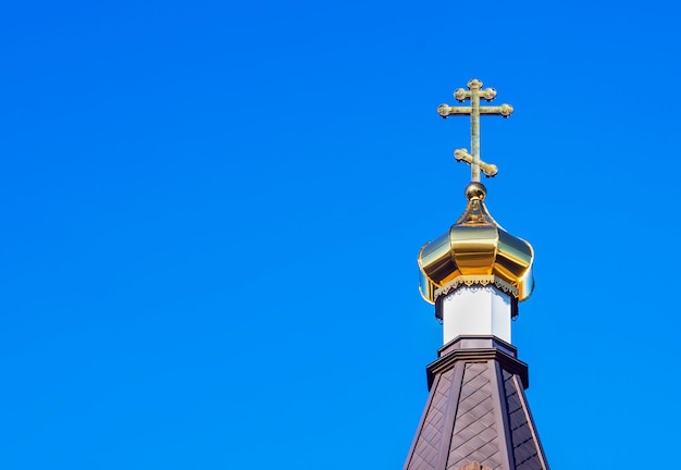 Le dôme doré d'un temple orthodoxe sur fond de ciel bleu et de nuages Croix d'or sur le dôme du temple