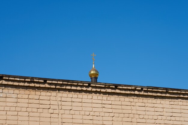 Le dôme de l'église derrière le mur de briques contre le ciel bleu clair.