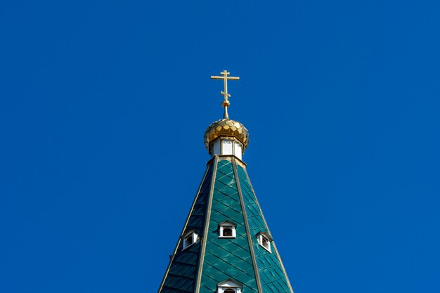 Dôme d'or avec une croix sur le toit vert de l'église orthodoxe russe