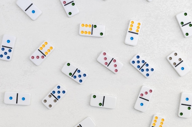 Photo dominos blancs avec des points colorés sur un fond de ciment blanc vue supérieure jeu de société