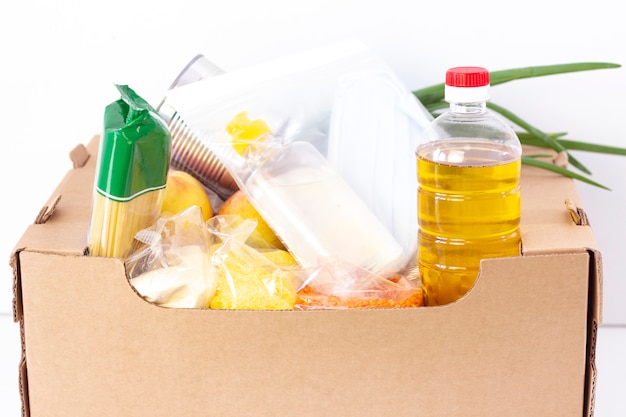 Don. boîte d'épicerie, aider les produits à ceux qui en ont besoin. boîte de don. boîte en carton avec des aliments essentiels sur une surface blanche.