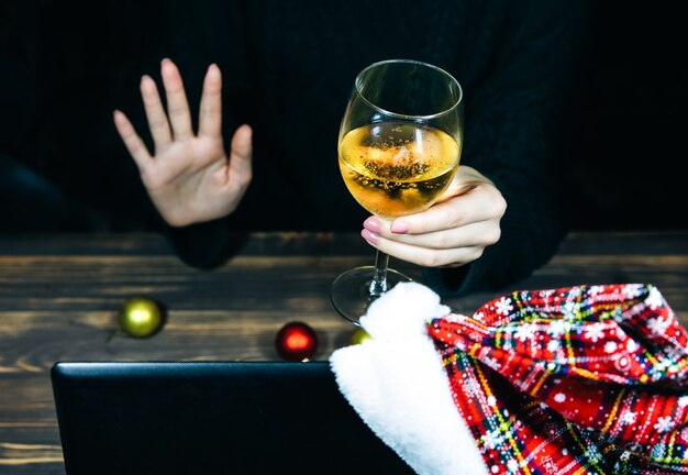 Don de cadeaux de Noël. Femme avec du champagne dans un verre parlant via des appels vidéo. Vacances dans l'isolement. Nouvelles décorations et lumières. Famille et amis célébrant en ligne. Ambiance chaleureuse.