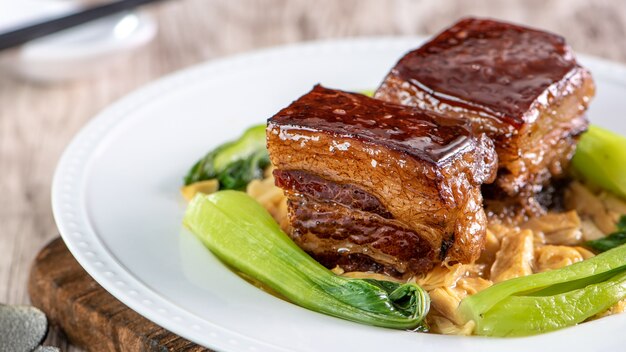 Dong Po Rou (viande de porc Dongpo) dans une belle assiette bleue avec des légumes de brocoli vert, nourriture festive traditionnelle pour le repas de cuisine du nouvel an chinois, gros plan.