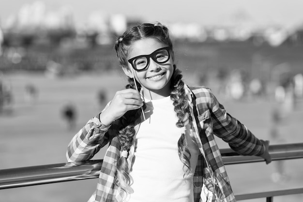 Donner à chaque enfant une enfance heureuse Adorable petite fille avec un sourire heureux et un regard drôle à travers des lunettes d'accessoires Heureux petit enfant avec un grand sourire le jour d'été Joyeuse journée internationale des enfants