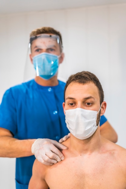 Donner à la clavicule un massage à un patient. Physiothérapie avec mesures de protection contre la pandémie de coronavirus, COVID-19. Ostéopathie, chiromassage thérapeutique